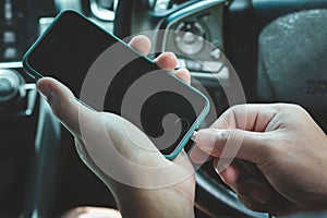 Hands man holding and charging battery mobile smartphone in car with cable in luxury interior car design. The phone is charging