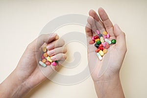 Hands of man holding colourful medicine pills isolate over white yellow background