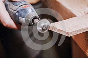 Hands of a man holding Dremel tool with an installed small cir