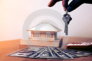 Hands man holding house keys with money and small house