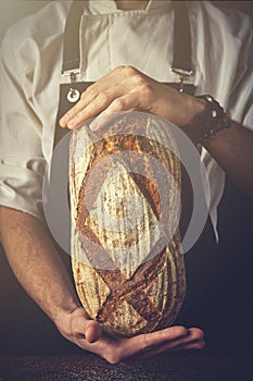 Hands of man holding oval bread