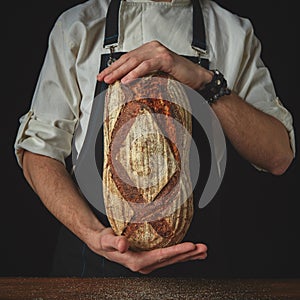 Hands of man holding oval bread