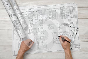 Hands of man holding a pencil over drawing layout in top view.