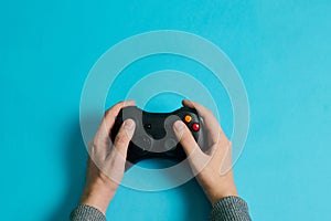 Hands of a man holding a video game console controller on a blue background