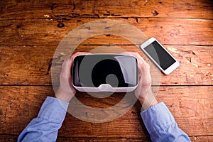 Hands of man holding virtual reality goggles and smartphone