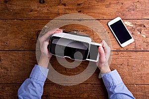 Hands of man holding virtual reality goggles and smartphone