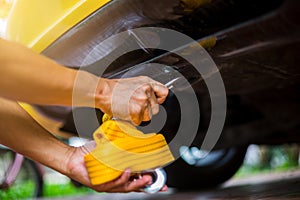 Hands of man holding yellow car towing strap with yellow car