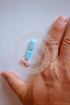 Hands of a man next to pills that symbolize a penis with an erection. Metaphor of male virility. Medicine related to male