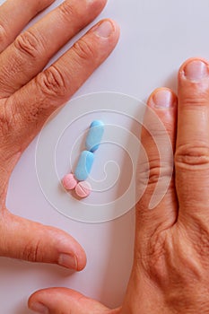 Hands of a man next to pills that symbolize a penis with an erection. Metaphor of male virility. Medicine related to male