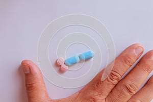 Hands of a man next to pills that symbolize a penis with an erection. Metaphor of male virility. Medicine related to male
