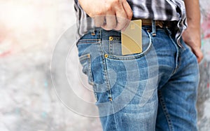Hands of man pick up empty gold generic credit card out of jeans pocket. Concept of losing money, business and finance