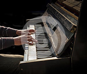 Hands of man playing an old piano