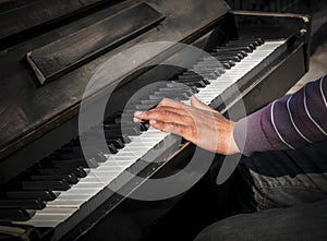 Hands of man playing an old piano