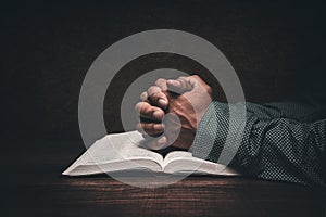 Hands of a man praying over an open bible