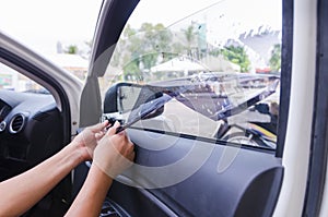 Hands of man removing old car window film photo