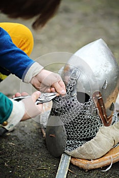 Hands of man, repaired armor of metal medieval helmet outdoor