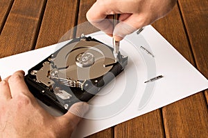 Hands of a man with a screwdriver disassembling the hard drive