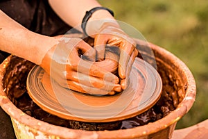 Potter work with clay. Hands of man in shape of heart in clay on pottery wheel mold vase.