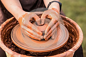 Potter work with clay. Hands of man in shape of heart in clay on pottery wheel mold vase.