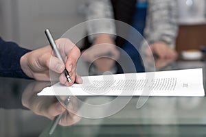 Hands of man signing formal paper and female hands