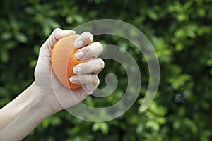 Hands of a man squeezing a orange stress ball