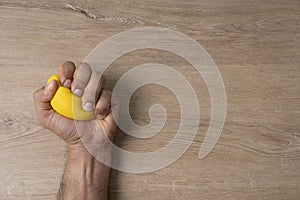 Hands of a man squeezing a yellow stress ball