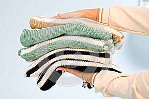 In the hands of a man is a stack of knitted clothes of different colors