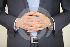 Hands of man in suit poses with folded hands and photo