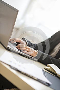 Hands of man in suit typing on laptop keyboard