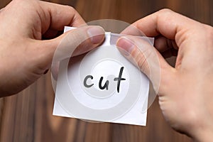 Hands of a man tearing a piece of paper with inscription cut