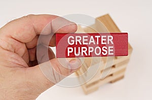 In the hands of a man there is a red wooden plate with the inscription - Greater Purpose