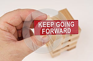 In the hands of a man there is a red wooden plate with the inscription - Keep Going Forward