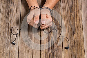 hands of man tied with phone headset, as the concept of man& x27;s dependence on music, technology