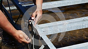 Hands of a man tighten a bolt and nut using an adjustable crescent wrench and a combination wrench.