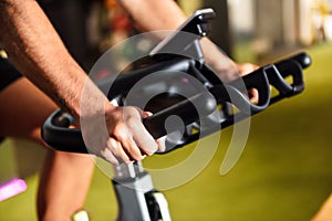 Hands of a man training at a gym doing cyclo indoor.