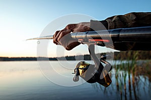 Hands of a man in a Urp plan hold a fishing rod, a fisherman catches fish at dawn. Fishing hobby vacation concept. Copy space