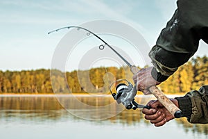 Hands of a man in a Urp plan hold a fishing rod, a fisherman catches fish at dawn. Fishing hobby vacation concept. Copy space