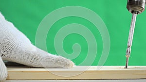 Hands of man using electric driller to spin the to the wood over green background