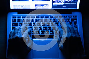 Hands of a man using laptop computer for hacking or steal data information at night in office.