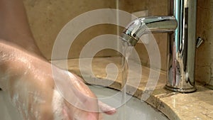 Hands of man wash their hands in a sink with foam to wash the skin and water flows through the hands. Concept of health