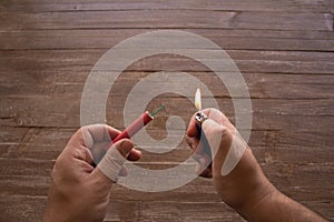 hands of a man who lights a firecracker with a lighter