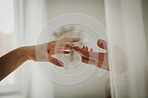 Hands of a man and a woman against the background of a blurred window. The gentle touch of a man and a woman. Love connection help