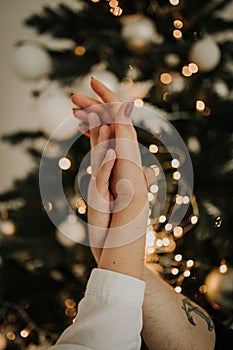 Hands of a man and a woman against the background of a New Christmas tree. The gentle touch of a man and a woman. Love connection