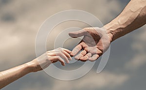 Hands of man and woman on blue sky background. Lending a helping hand. Giving a helping hand. Solidarity, compassion