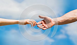 Hands of man and woman on blue sky background. Lending a helping hand. Solidarity, compassion, and charity, rescue
