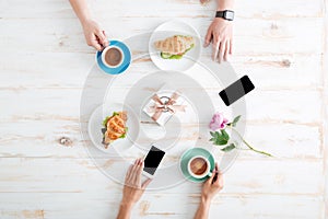 Hands of man and woman eating croissants with coffee