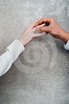 The hands of a man and a woman exchange wedding rings.