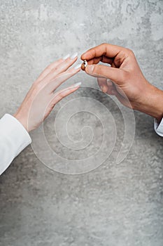 The hands of a man and a woman exchange wedding rings.