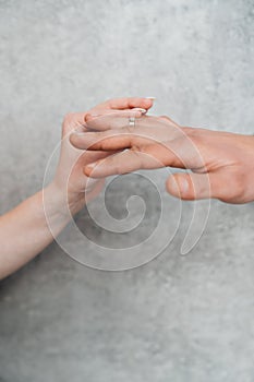 The hands of a man and a woman exchange wedding rings.