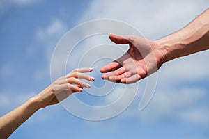 Hands of man and woman reaching to each other, support. Giving a helping hand. Hands of man and woman on blue sky